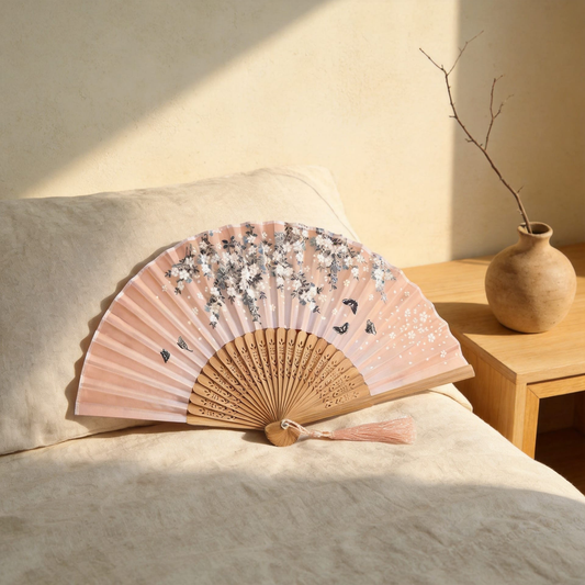 Sakura™ Silk Hand Fan lying open on oatmeal linen in a warm Japandi bedroom