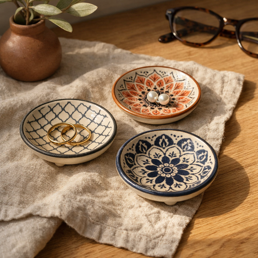 Three Cove trinket dishes on a linen-draped oak vanity holding gold rings and pearl stud earrings
