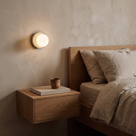 Cream Orb sconce glowing above a floating oak nightstand beside a linen bed