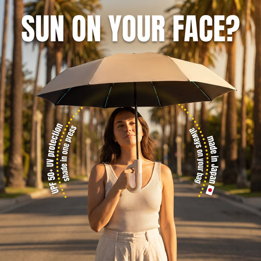 Woman walking under an open beige Haven umbrella on a sunny palm-lined street