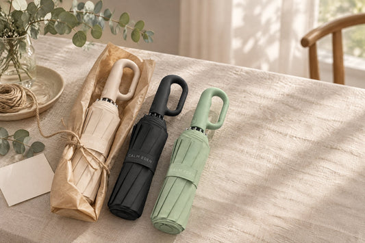 Beige, black and green Haven Umbrellas on a table, one wrapped in kraft paper