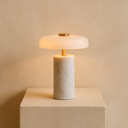 Roam portable marble lamp glowing on a warm cream plaster plinth