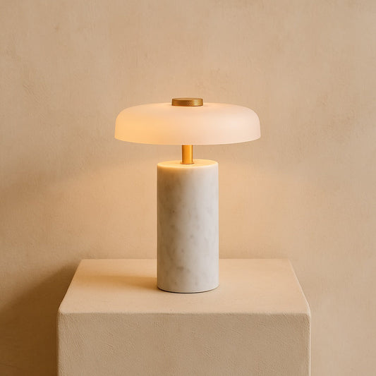 Roam portable marble lamp glowing on a warm cream plaster plinth