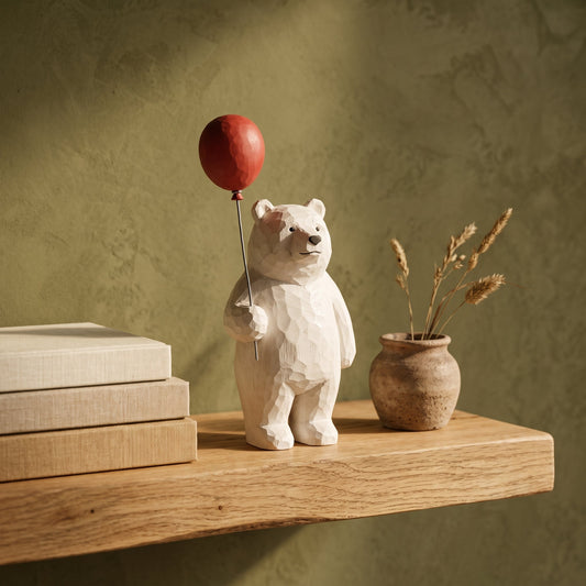 Bruin™ Carved Bear Ornament with red balloon on an oak shelf in Calm Eden style