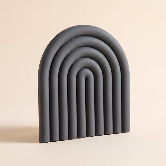 Vault™ Arch Trivet — charcoal ribbed silicone arch on warm cream background