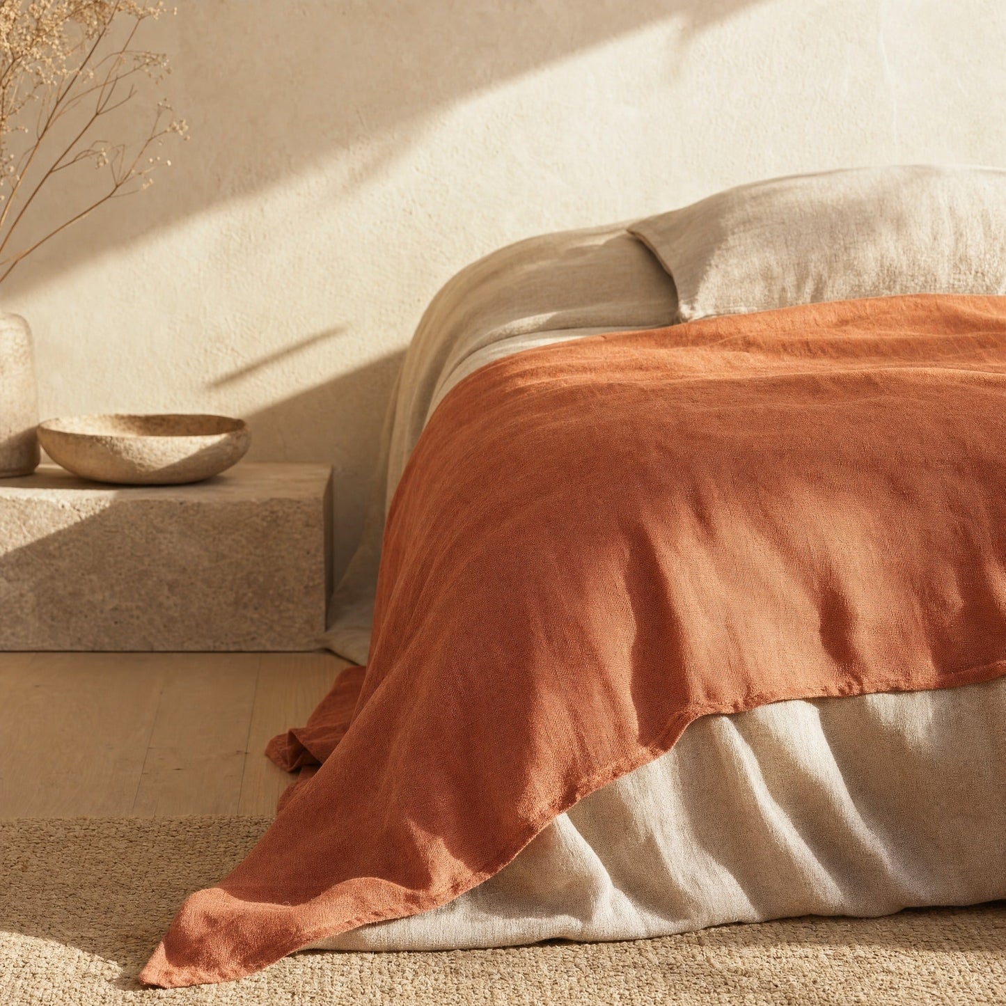 Clay linen sheet draped over bed corner in golden morning light