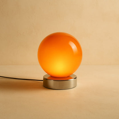 Ember glass globe lamp glowing on warm cream plaster