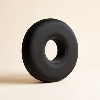 Ring™ Ear Relief Pillow — charcoal donut pillow with centre ear hole on warm cream background