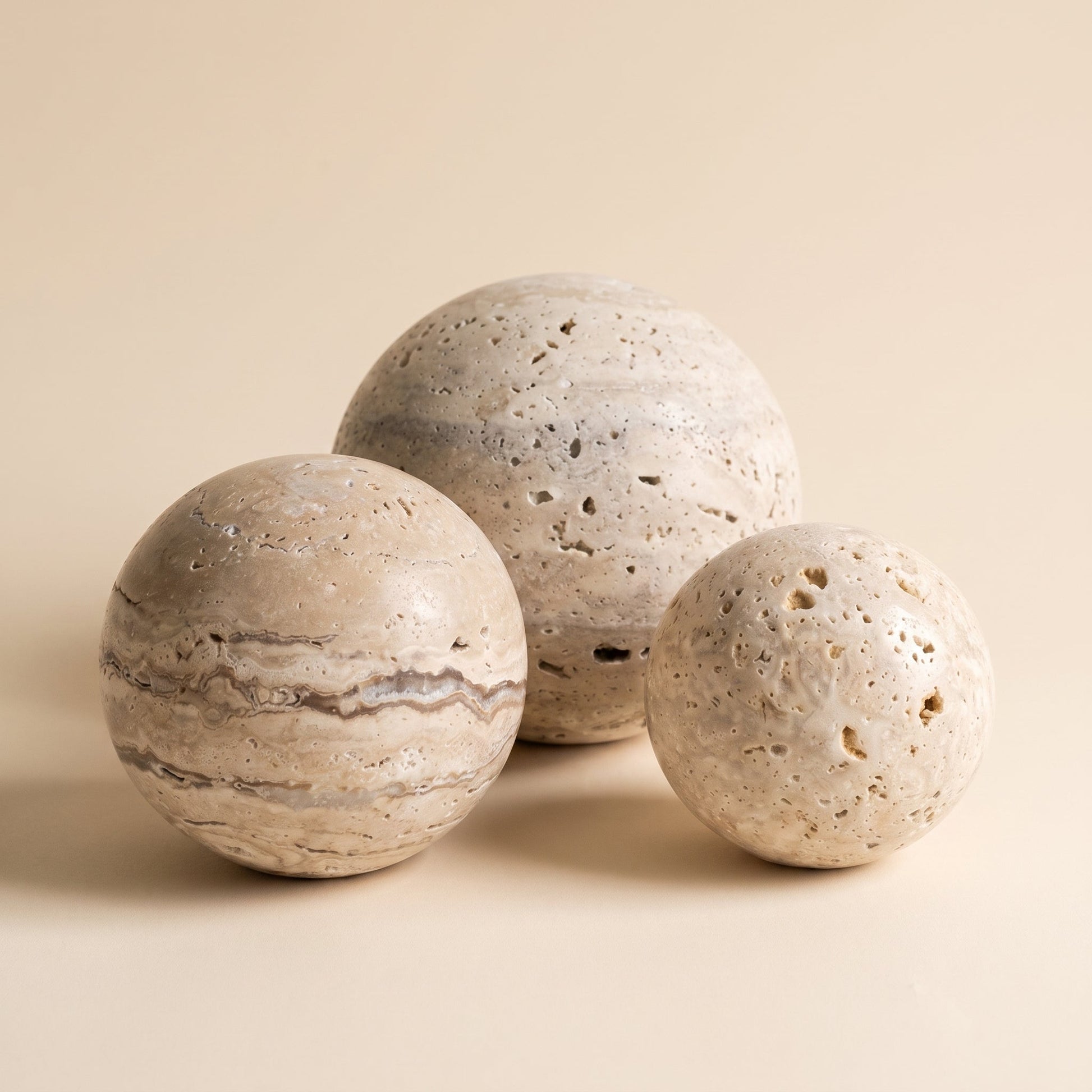 Tivoli™ Stone Sphere — three travertine spheres on warm cream background