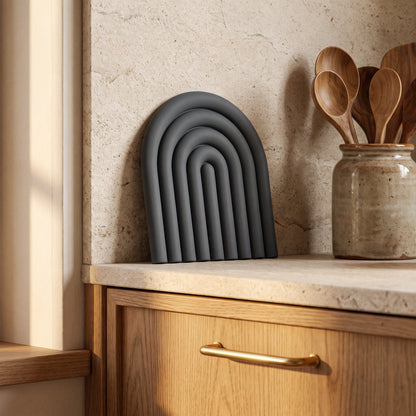 Vault™ Arch Trivet leaning against the stone backsplash in a warm Calm Eden-style kitchen