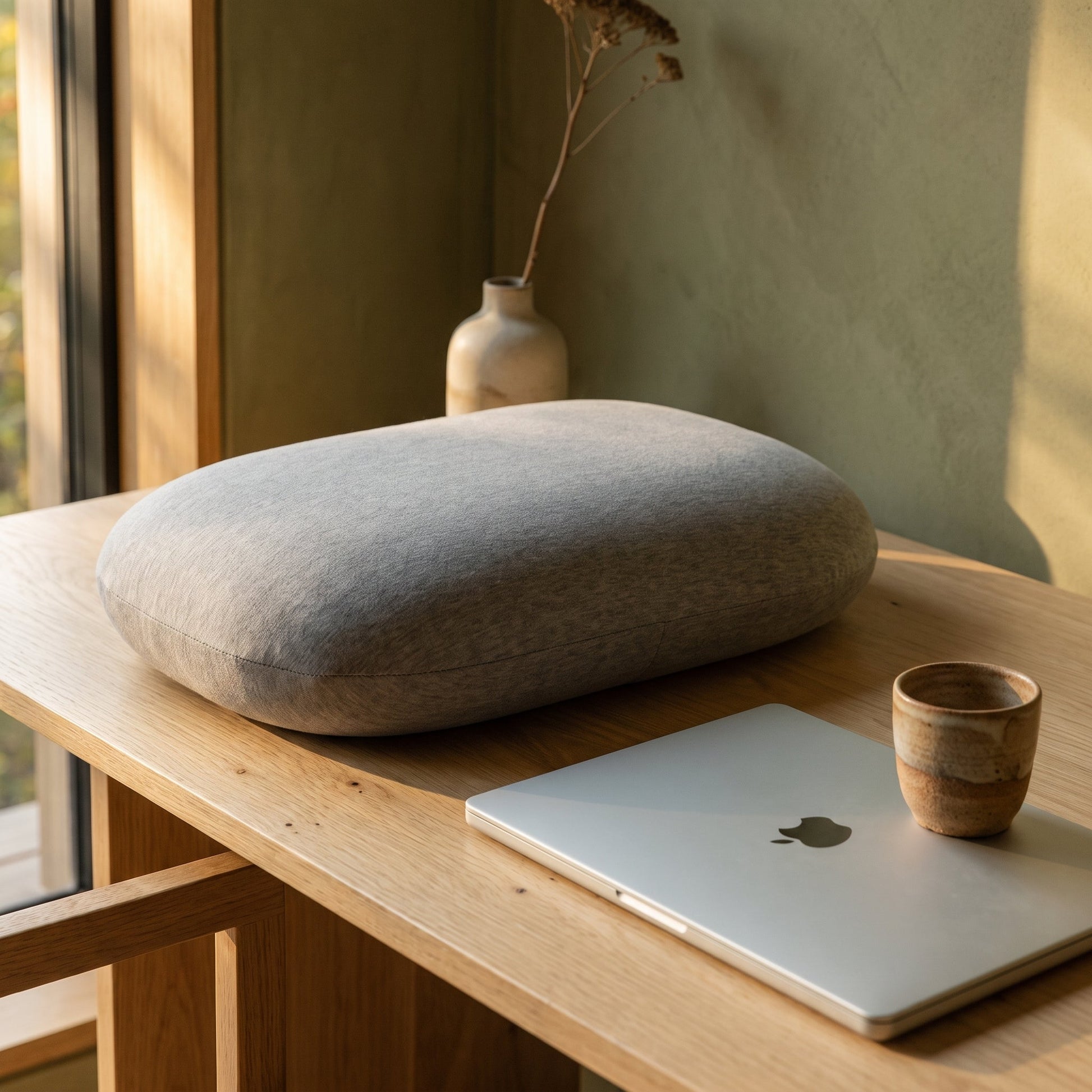 Doze™ Desk Nap Pillow resting on a pale-oak desk in the Calm Eden interior