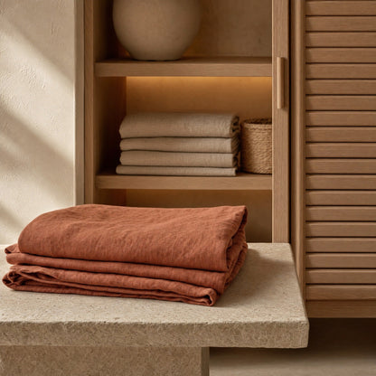 Folded clay linen sheet on stone bench in oak closet