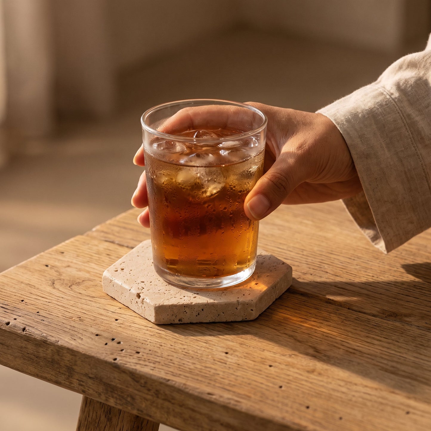 Setting an iced tea down on the hexagon Strata™ Travertine Coaster