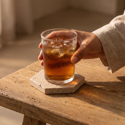 Setting an iced tea down on the hexagon Strata™ Travertine Coaster