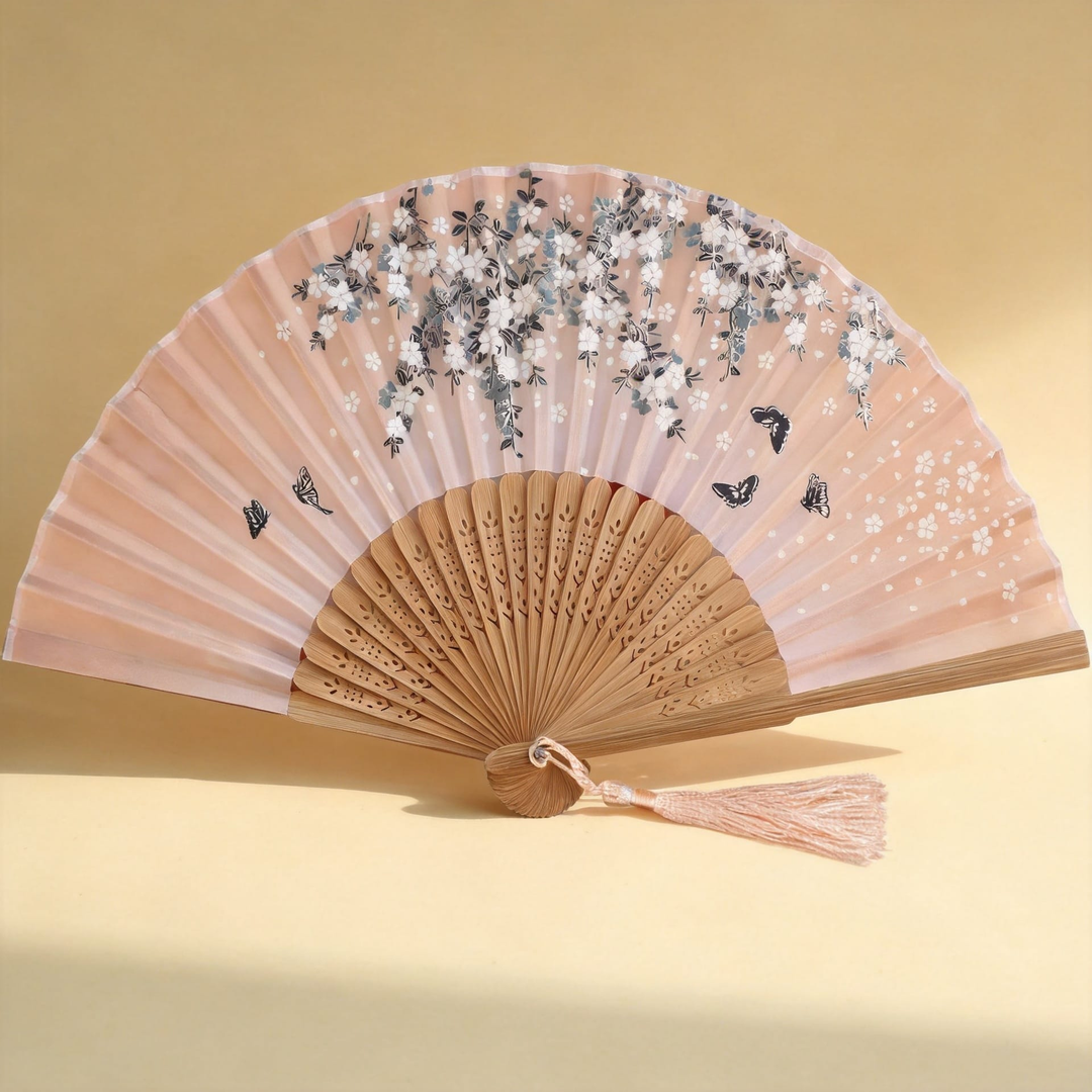 Sakura™ Silk Hand Fan — blush silk fan with sakura print and carved bamboo ribs on warm cream background