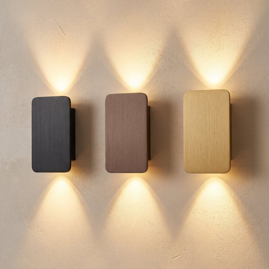 Beam™ Wall Sconce — charcoal, bronze and brass brushed-aluminum sconces lit on warm cream plaster