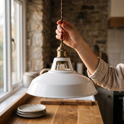 A woman adjusting the braided cord of a Brim Pendant above a kitchen counter