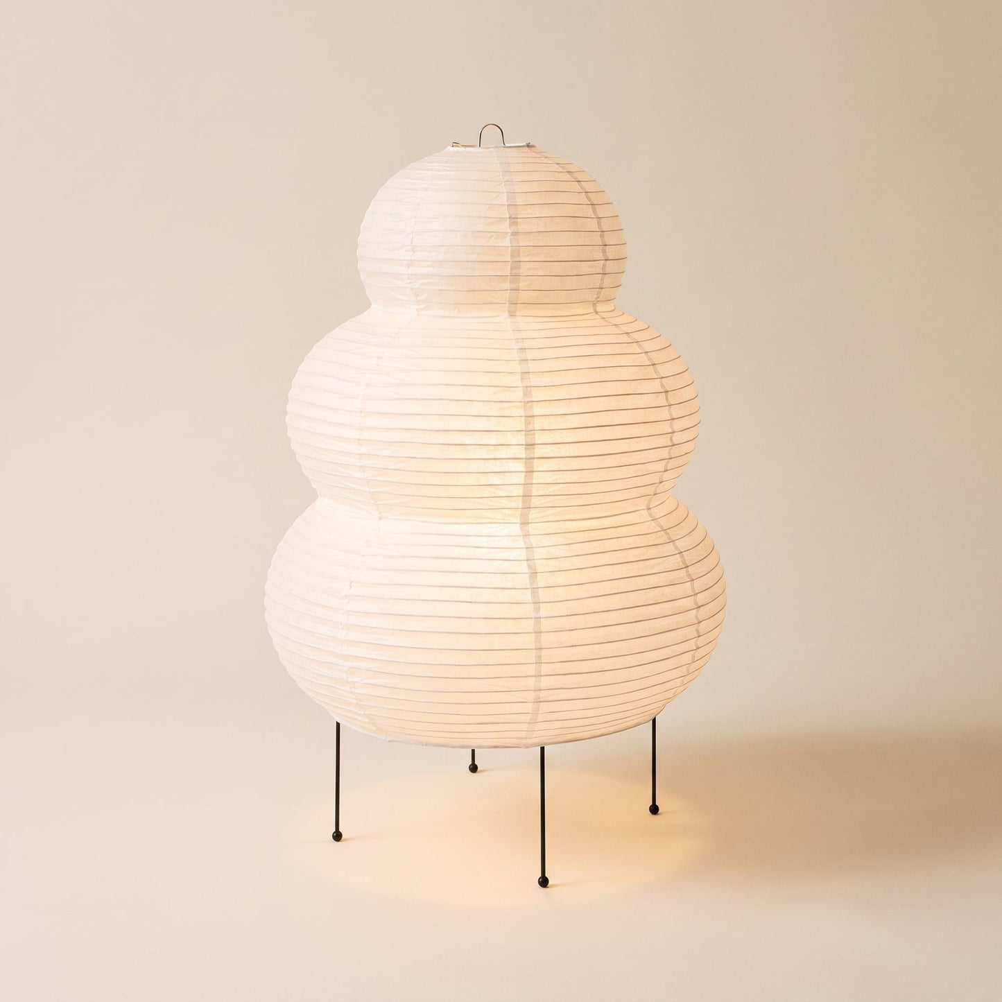 Cocoon™ Paper Table Lamp — triple-tier rice-paper lamp glowing on warm cream background