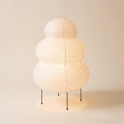 Cocoon™ Paper Table Lamp — triple-tier rice-paper lamp glowing on warm cream background