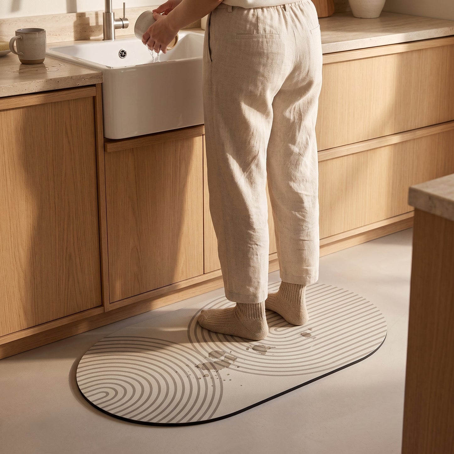 Washing up while standing on the Stone™ Quick-Dry Kitchen Mat as drips vanish