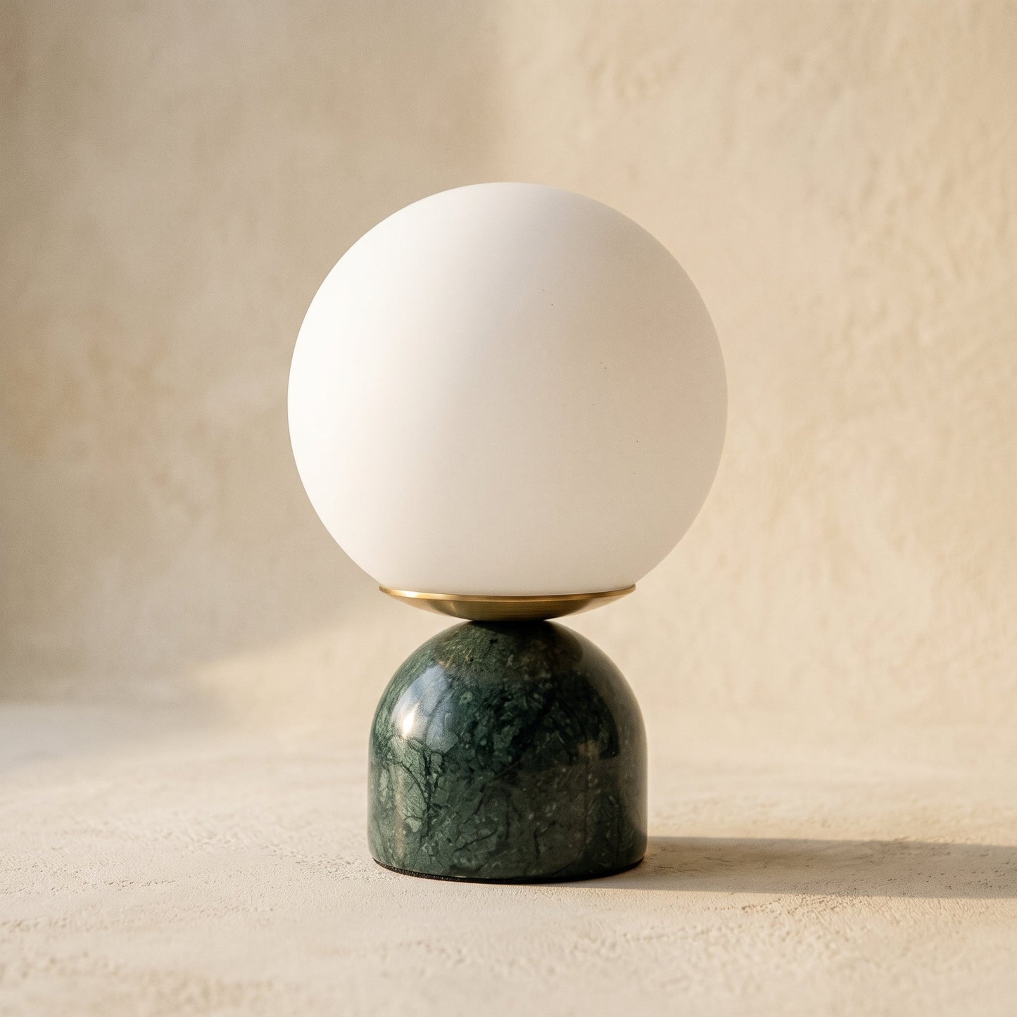 Cobble™ Marble Lamp — opal glass globe on a verde green marble dome base, on warm cream plaster