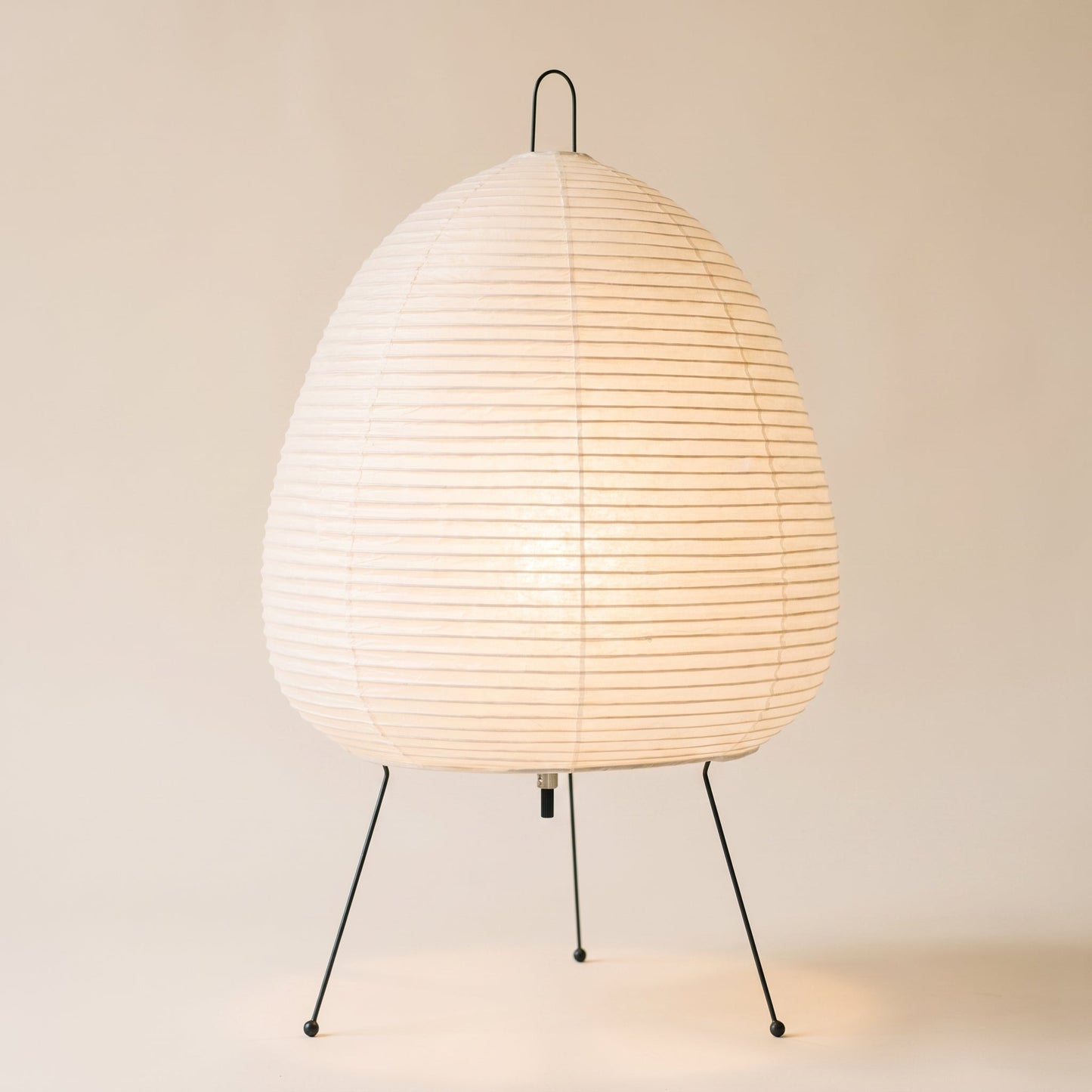 Washi™ Paper Lantern Lamp — rice-paper lantern on wire legs glowing on warm cream background