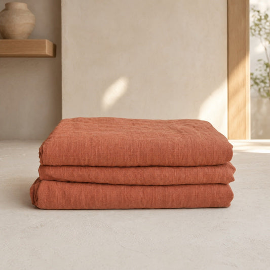 Flax clay French linen flat sheet folded stack on warm limewash plaster
