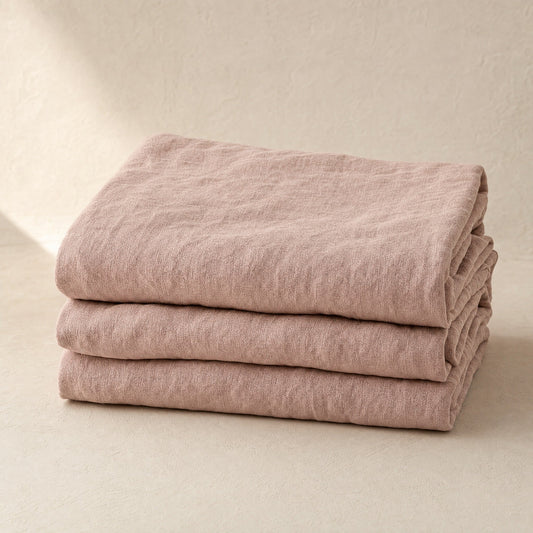 Flax blush French linen flat sheet folded stack on warm limewash plaster