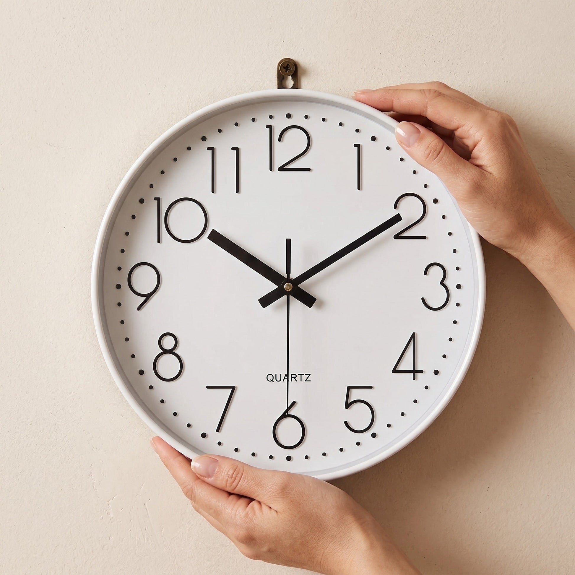 Hands settling the Hush Clock onto a brass wall hook