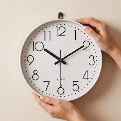Hands settling the Hush Clock onto a brass wall hook