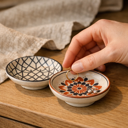 A hand lowering a slim gold ring into a Cove trinket dish on a bedside table