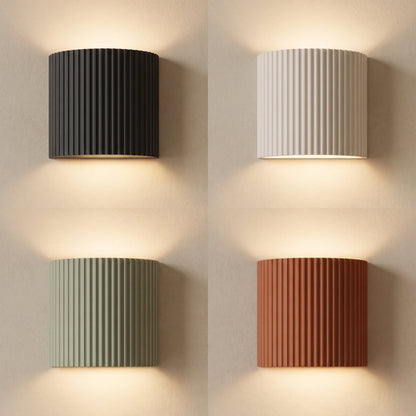 Flute fluted wall sconces in charcoal, white, sage and terracotta lit on warm cream plaster