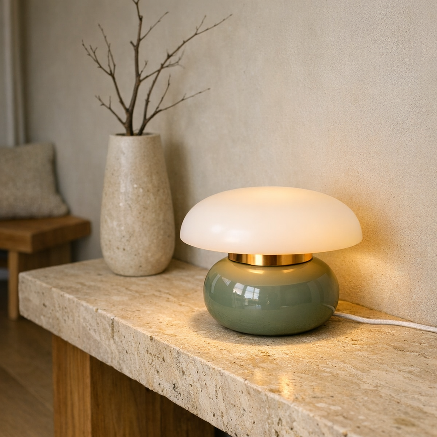 Pillar Dome Lamp in Sage Green lit on a travertine console in a minimalist room