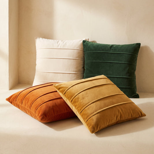 Pleat velvet cushion covers in ivory, forest, amber and ochre on warm cream plaster