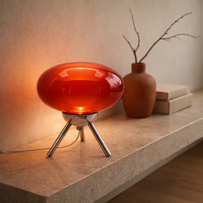 Ruby™ Glass Mushroom Lamp lit on a travertine console beside a terracotta vessel and stacked books in a modern minimalist room