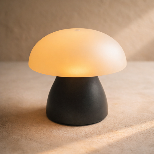 Truffle Cordless Lamp, small mushroom lamp with glowing opal cap and charcoal base, on warm cream plaster