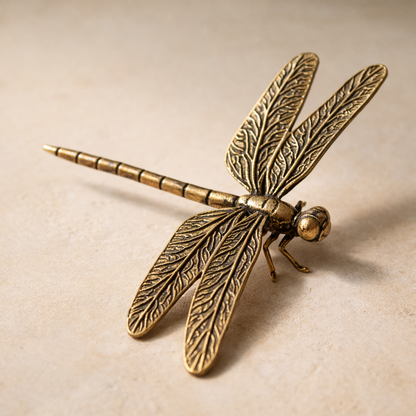 Reed brass dragonfly figurine on warm cream plaster, wings raised, antique brass patina