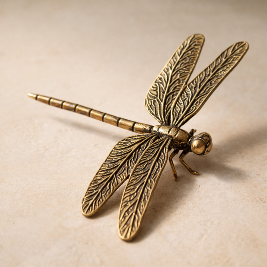 Reed brass dragonfly figurine on warm cream plaster, wings raised, antique brass patina