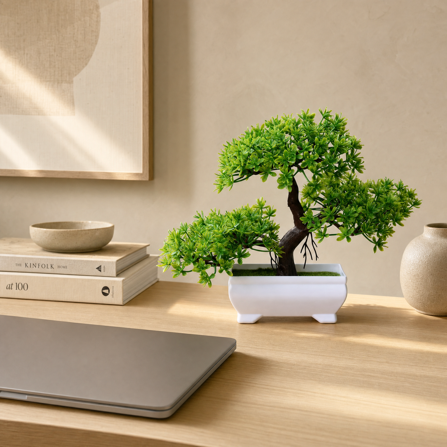 Faux bonsai on a desk beside a laptop