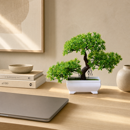 Faux bonsai on a desk beside a laptop