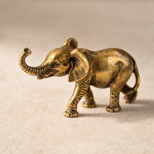 Tusk solid cast brass elephant figurine, trunk raised, on warm cream plaster